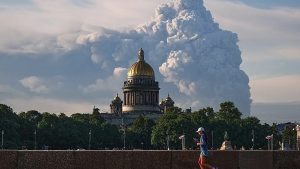 Жінка біжить перед золотим куполом собору на тлі величезної хмари диму